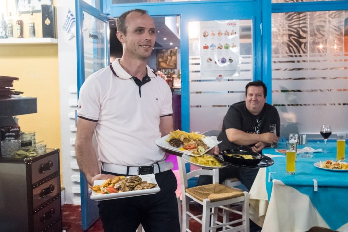 Astrit der Chef serviert Essen auf der Terrasse des griechischen Restaurants Mykonos am Faakersee